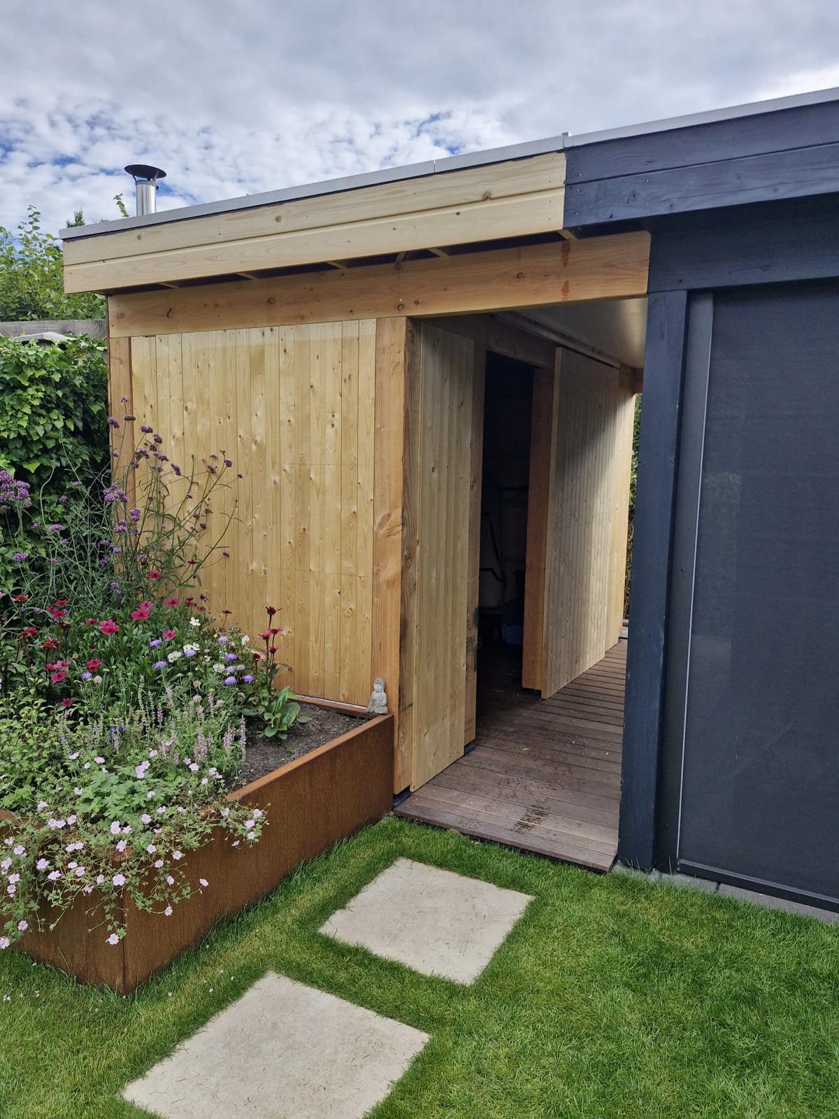 Nieuw houten tuinhuisje met overkapping, vlonder en bloembakken in de tuin