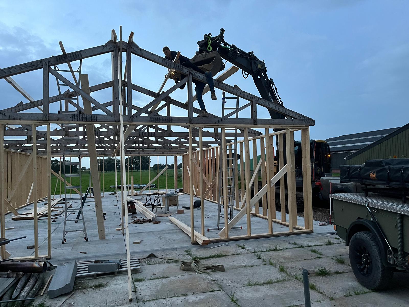 Kapconstructie van een houten schuur in aanbouw op het erf